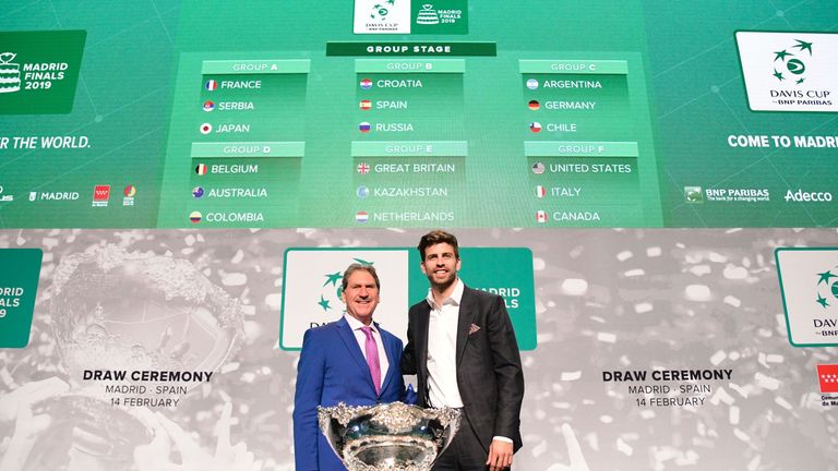 International Tennis Federation (ITF) president David Haggerty (L) and Barcelona's Spanish defender and Kosmos president Gerard Pique pose with the trophy in front of a screen showing the groups after the draw for the 2019 Davis Cup tennis finals in Madrid on February 14, 2019.