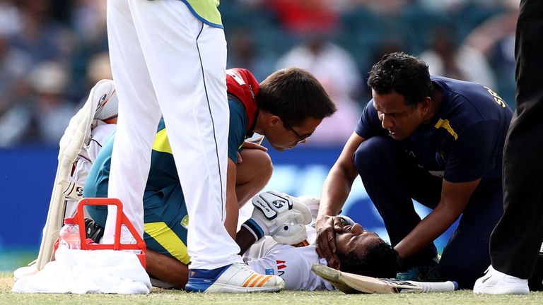 Sri Lanka's Dimuth Karunaratne receives medical attention after being struck by a delivery from Pat Cummins of Australia during day two of the Second Test match in Canberra.