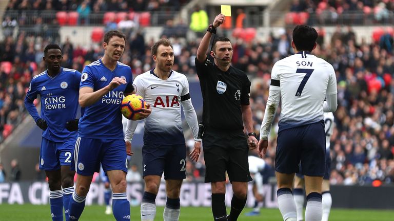 Referee Michael Oliver shows a yellow card to Tottenham Hotspur's Heung-Min Son