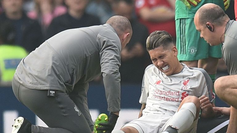 Roberto Firmino winces in pain while receiving treatment during the first-half
