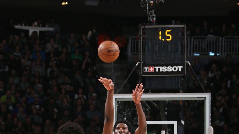 Joel Embiid launches a three-pointer over Giannis Antetokounmpo