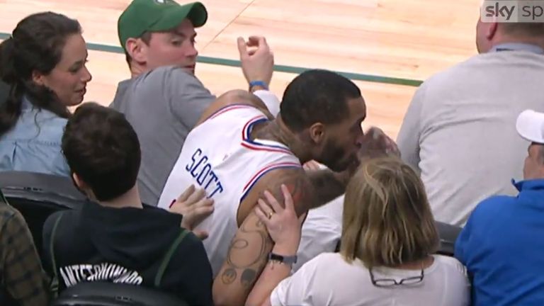 Mike Scott takes a swig from a fan's drink after tumbling into the crowd in Milwaukee