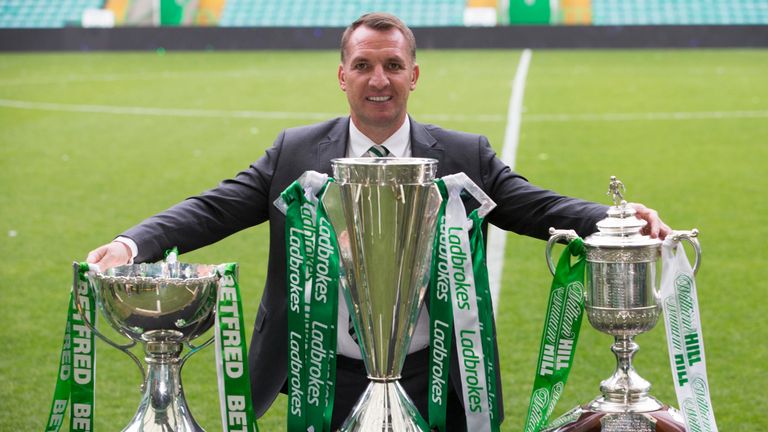 Brendan Rodgers poses with Scottish Premiership, Scottish Cup and Scottish League Cup trophies