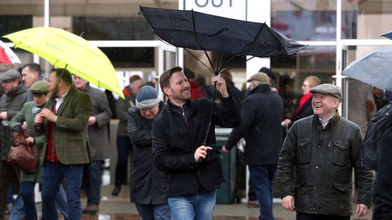 A racegoer adjusts his umbrella in the rain at Cheltenham on Tuesday.