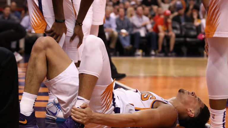 Devin Booker #1 of the Phoenix Suns holds his ankle after an injury during the first half of the NBA game against the Utah Jazz at Talking Stick Resort Arena on April 03, 2019 in Phoenix, Arizona.