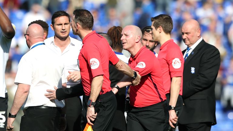 A match official pulls referee Simon Hooper away from Derby County manager Frank Lampard after an exchange of words