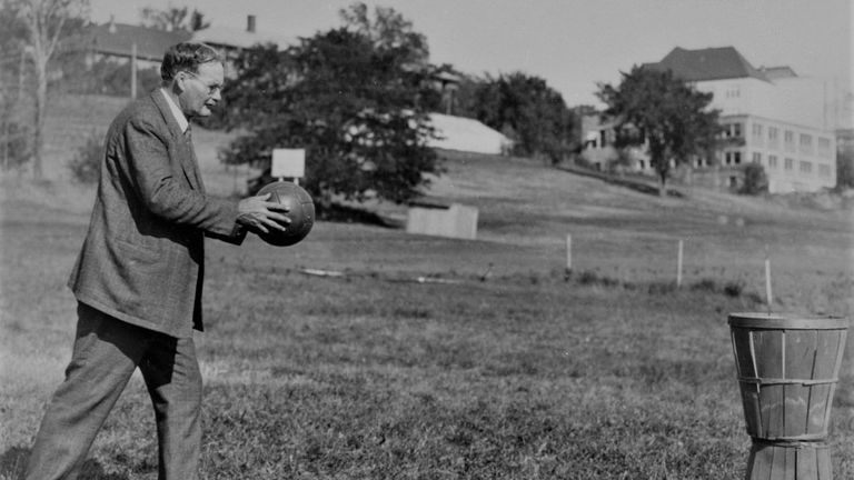 Dr James Naismith with a soccer ball and peach basket