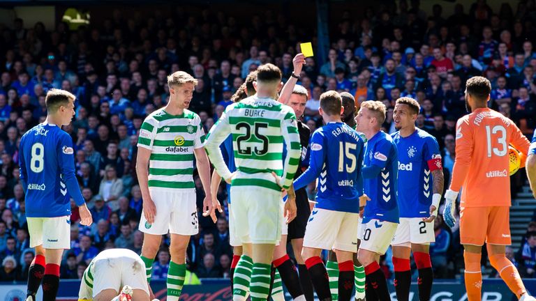 Referee Kevin Clancy books Rangers' Jon Flanagan (R) after a clash with Celtic's Scott Brown