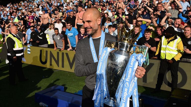 Pep Guardiola celebrates with the Premier League trophy in front of Manchester City fans at the AMEX Stadium