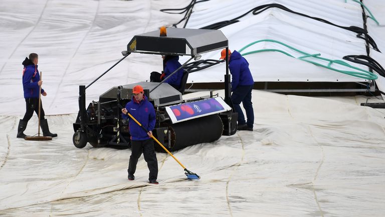Ground staff work on the covers as play is delayed due to rain during the group stage match of Cricket World Cup between Bangladesh and Sri Lanka