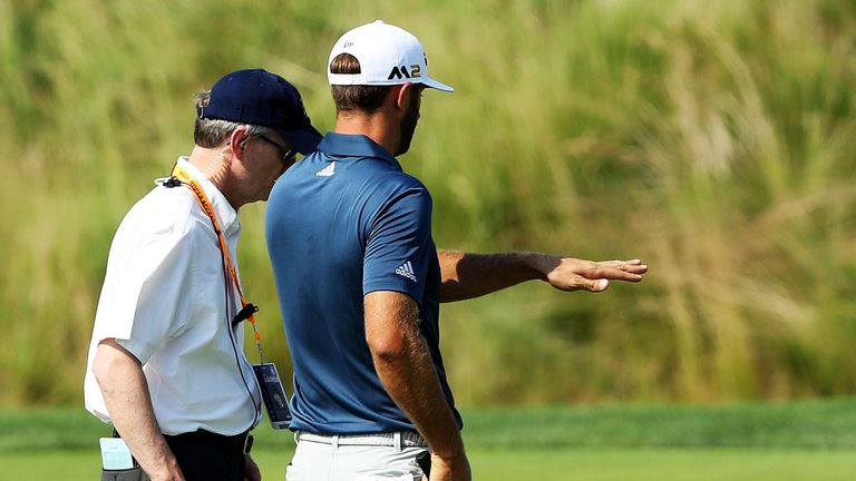 Dustin Johnson chats with a rules official on the fifth green during the final round in 2016