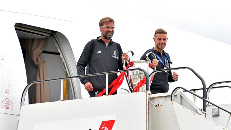 Jurgen Klopp and Jordan Henderson emerge from the plane with the Champions League trophy