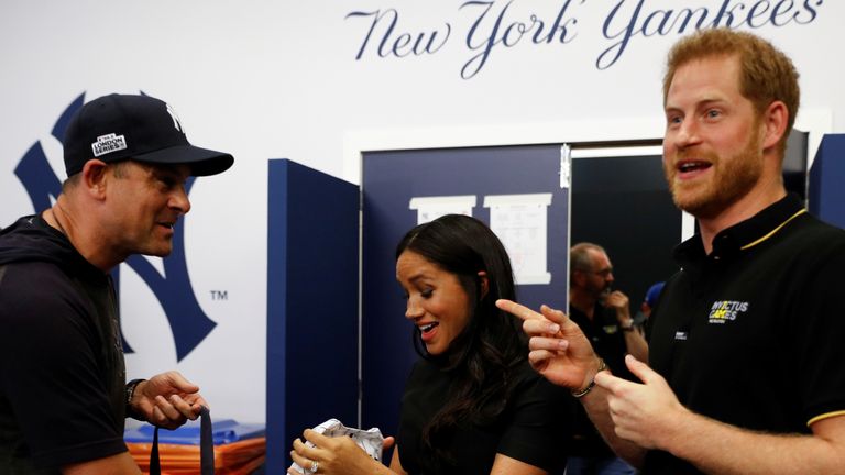 Manager Aaron Boone of the New York Yankees presents a gift for Archie to Prince Harry, Duke of Sussex and Meghan, Duchess of Sussex before their game against the Boston Red Sox