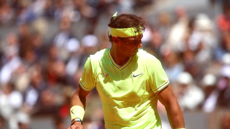 Rafael Nadal shields himself against the clay in the windy conditions