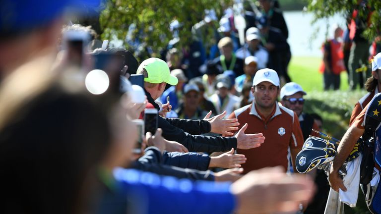 Spectators hold their hands out as Europe's Italian golfer Francesco Molinari walks past during his foursomes match on the second day of the 42nd Ryder Cup at Le Golf National Course at Saint-Quentin-en-Yvelines, south-west of Paris, on September 29, 2018.