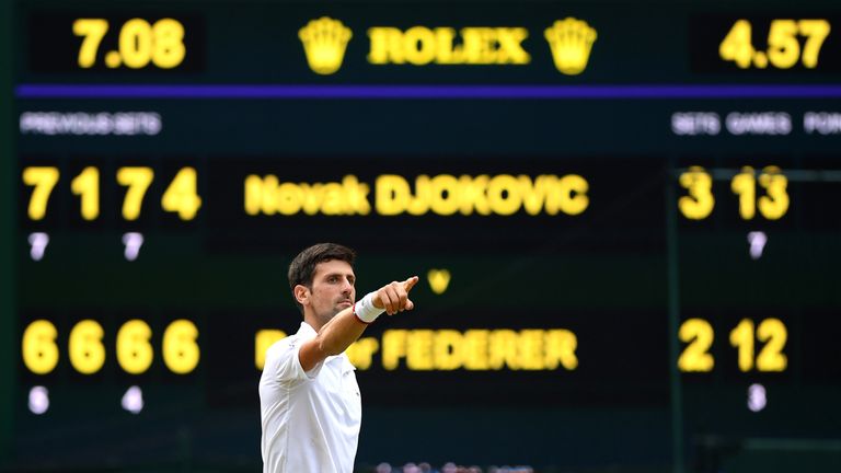 Novak Djokovic celebrates with electronic scoreboard in the background
