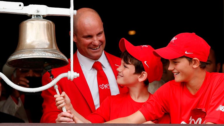 Former England cricketer Andrew Strauss (back) and his two sons Luca (L) and Sam (R) ring the five minute bell dressed in red 