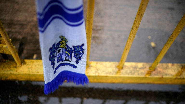 A scarf hangs from the locked gate of Gigg Lane