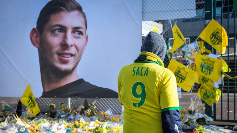 Supporters pay tribute and look at yellow flowers displayed in front of the portrait of Argentinian forward Emiliano Sala at the Beaujoire stadium in Nantes, on February 10, 2019