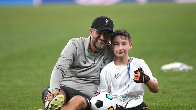 Jurgen Klopp poses for a photo with a child from the UEFA Foundation at the Vodafone Arena