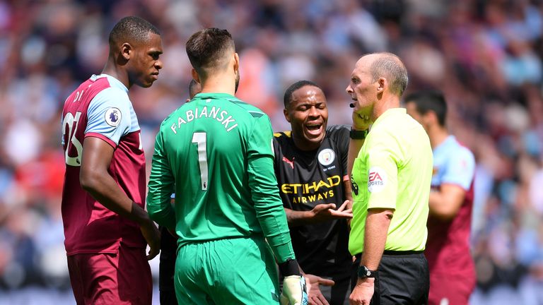 Players from both sides gather around referee Mike Dean after Manchester City's third goal is disallowed by VAR