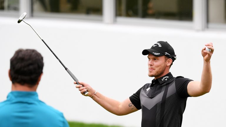 Danny Willett takes the acclaim of the crowd on the 18th green at Wentworth as Jon Rahm watches on 