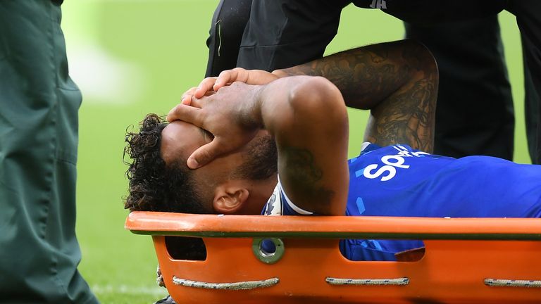 Theo Walcott receives medical treatment after being hit on the head by a Raheem Sterling cross