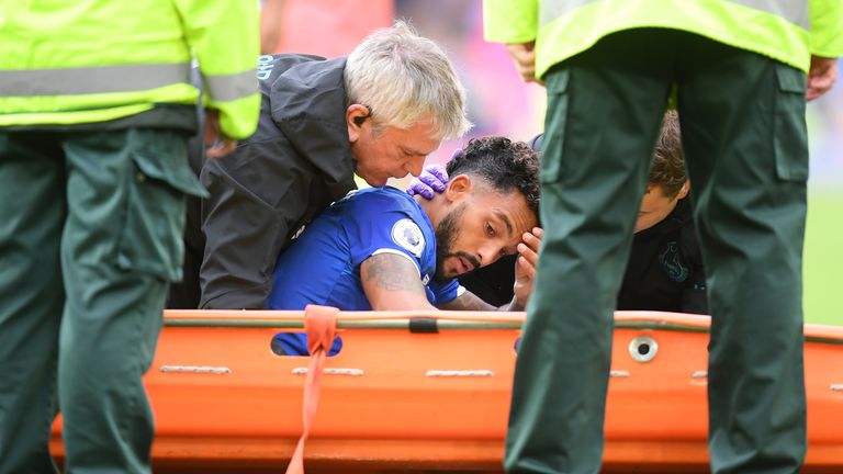 Theo Walcott receives medical treatment after being hit on the head by a Raheem Sterling cross