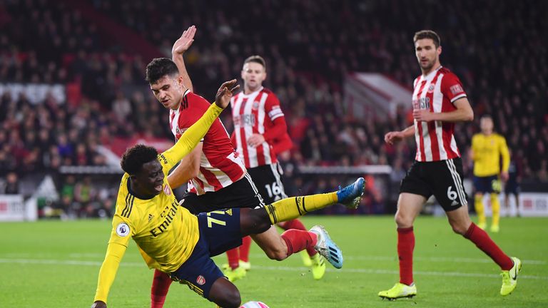 Bukayo Saka of Arsenal goes down after he battles for possession with John Egan of Sheffield United