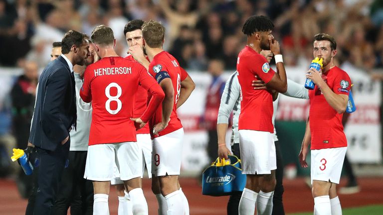 England players talk amongst themselves during a temporary break in play following racist chanting from a section of the home support