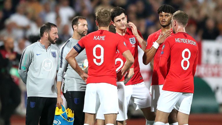 England players talk amongst themselves during a temporary break in play following racist chanting from a section of the home support