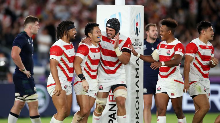 Japan celebrate their bonus-point try against Scotland