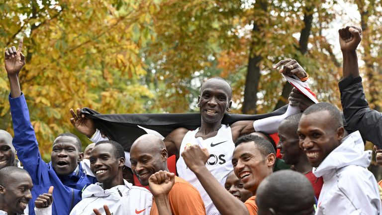 Kenya's Eliud Kipchoge (white jersey) celebrates after busting the mythical two-hour barrier for the marathon on October 12 2019 in Vienna. - Kipchoge holds the men's world record for the distance with a time of 2hr 01min 39sec, which he set in the flat Berlin marathon on September 16, 2018. He tried in May 2017 to break the two-hour barrier, running on the Monza National Autodrome racing circuit in Italy, failing narrowly in 2hr 00min 25sec. (Photo by HERBERT NEUBAUER / APA / AFP) / Austria OUT