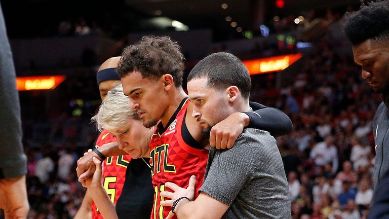 Atlanta Hawks point guard Trae Young is helped from the court after injuring his ankle