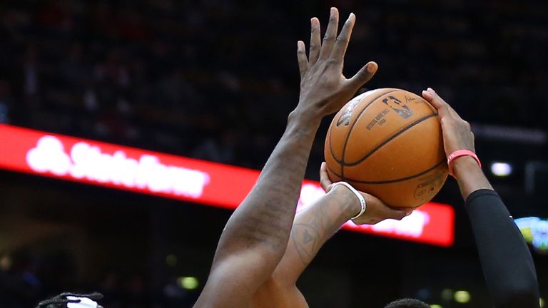 Jrue Holiday challenges a Paul George jump shot