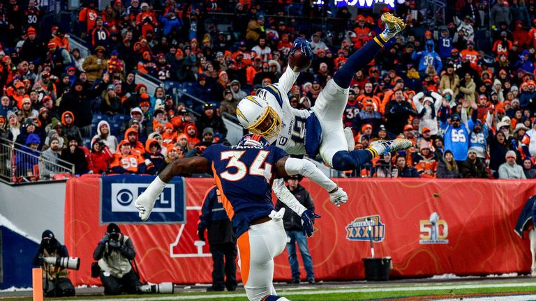 Keenan Allen #13 of the Los Angeles Chargers leaps over Will Parks #34 of the Denver Broncos to score a third quarter touchdown on a reception at Empower Field at Mile High on December 1
