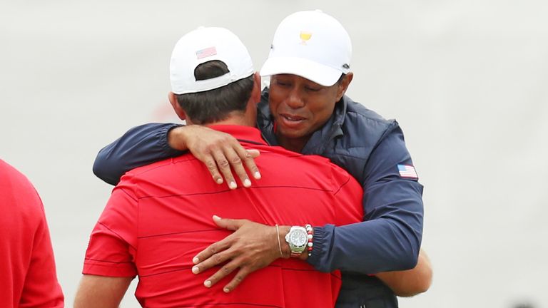 Tiger Woods abraza a Reed después de su victoria individual