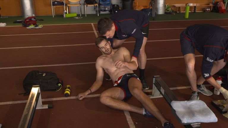 A rower collapses into the arms of one of the support staff