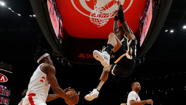 John Collins dangles from the rim following a dunk against the LA Clippers