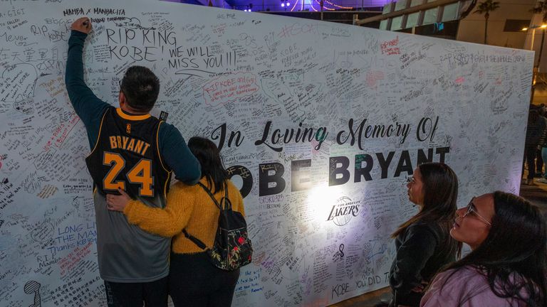 A Lakers fan writes his tribute to Kobe Bryant on a wall of remembrance at Staples Center