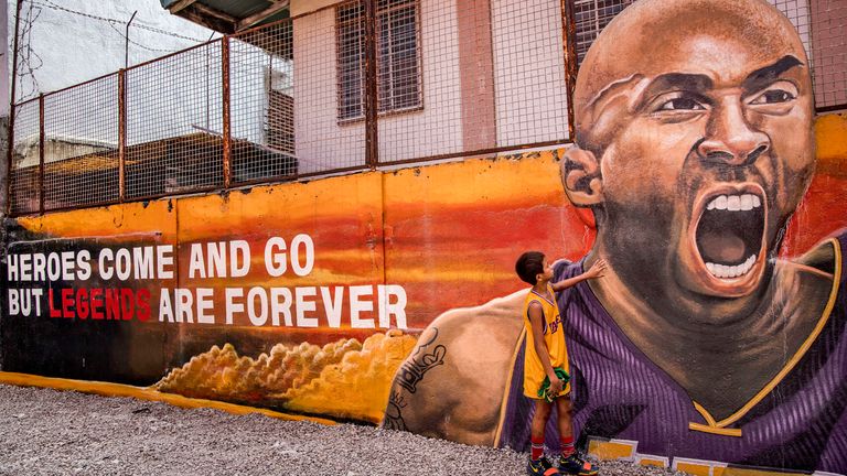 A child stands next to a mural of late NBA star Kobe Bryant outside the "House of Kobe" basketball court on January 28, 2020 in Valenzuela, Metro Manila, Philippines