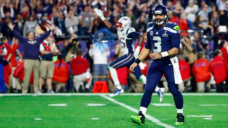 Wilson walks off the field to New England celebrations after his heartbreaking interception secured a Super Bowl XLIX win for the Patriots