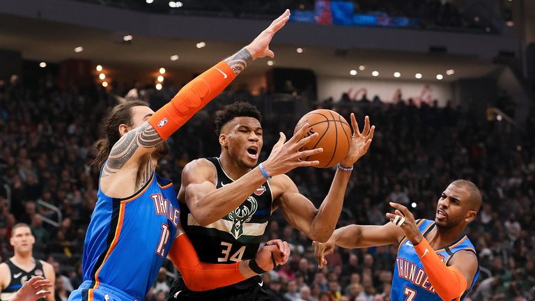Giannis Antetokounmpo of the Milwaukee Bucks dribbles the ball while being guarded by Steven Adams  and Chris Paul of the Oklahoma City Thunder