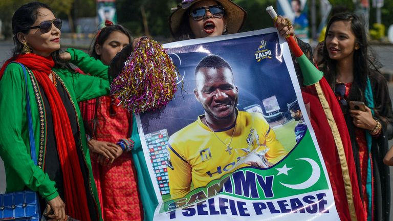 Spectators carry a poster featuring an image of Peshawar Zalmi's team captain Darren Sammy outside the National Cricket Stadium in Karachi on February 21, 2020, ahead of the start of the Pakistan Super League (PSL) T20 cricket match between Peshawar Zalmi and Karachi Kings.