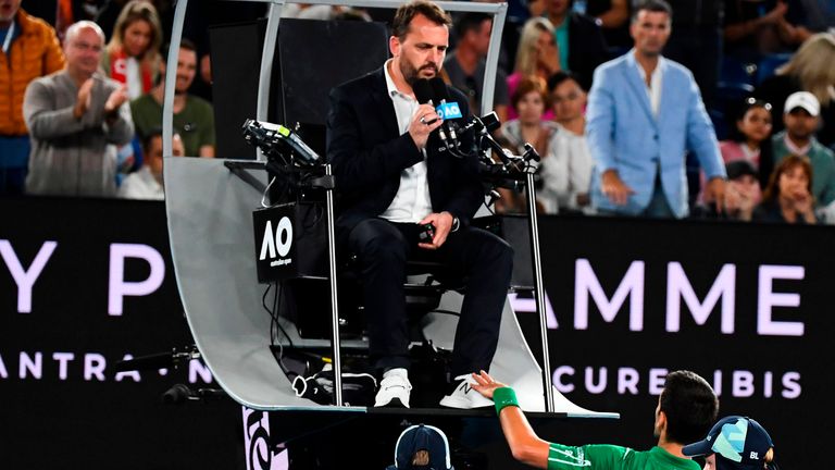 Serbia's Novak Djokovic (R) pats the feet of the umpire as he plays against Austria's Dominic Thiem during their men's singles final match on day fourteen of the Australian Open tennis tournament in Melbourne on February 2, 2020