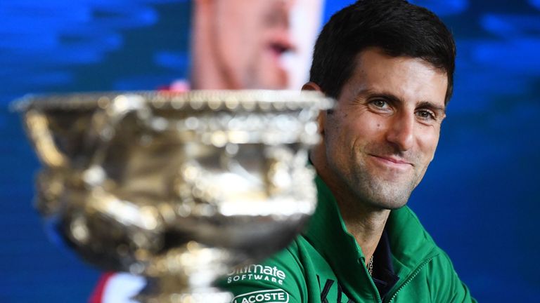 Serbia's Novak Djokovic smiles as he sits beside the Norman Brookes Challenge Cup trophy during a press conference after beating Austria's Dominic Thiem in their men's singles final match on day fourteen of the Australian Open tennis tournament in Melbourne on February 3, 2020.