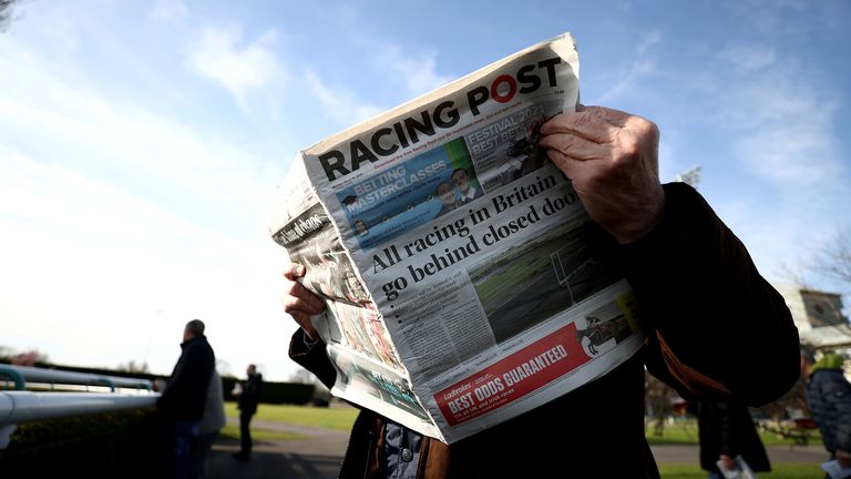 A racegoer reads the Racing Post at Southwell Racecourse.