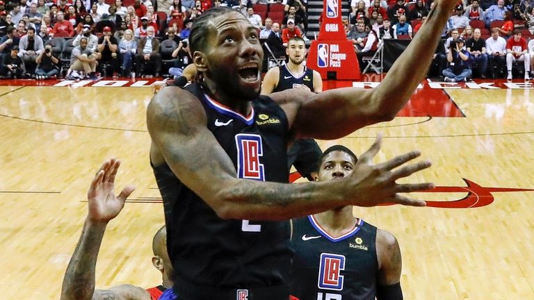 Kawhi Leonard drives to the basket while defended by James Harden