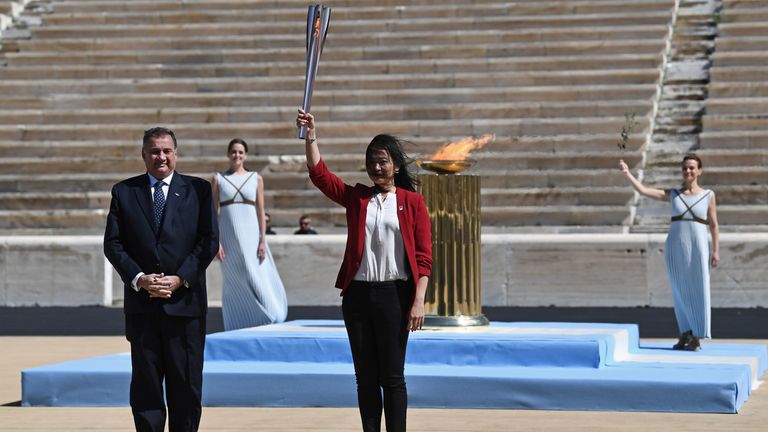 Former Japanese swimmer Imoto Naoko (R) holds the Olympic torch next to Greek Sports Minister and HOC President Spyros Capralos (L) during the olympic flame handover ceremony for the 2020 Tokyo Summer Olympics, on March 19, 2020 in Athens. - The ceremony is held behind closed doors as a preventive measure against the spread of the Covid-19 caused by the novel Coronavirus. (Photo by ARIS MESSINIS / POOL / AFP)