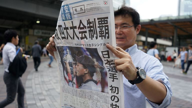 A pedestrian reads an extra edition Japanese newspaper reporting on tennis player Naomi Osaka's victory at the US Open, in Tokyo on September 9, 2018. 